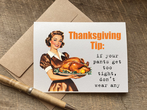 Thanksgiving-themed card with a vintage illustration of a woman holding a roasted turkey, on a wooden surface. that reads: "thanksgiving tip:
if your pants get too tight, don’t wear any"