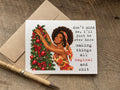 funny christmas card with a black african american retro woman by a tree that says: don't mind me, i'll just be over here making thangs all magical and shit