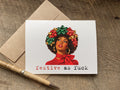 a funny christmas greeting card with a retro-style illustration of a Black woman wearing a red bow and green-and-red bow headpiece, with the text 'festive as fuck' printed below. 