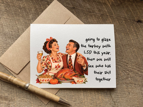 funny thanksgiving card with a retro couple laughing at dinner that says: going to glaze the turkey with LSD this year. then we will see who has their shit together