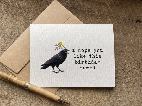 funny birthday card with a raven or crow wearing a birthday hat that says: "i hope you like this birthday cawed"