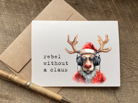 funny christmas Card with reindeer wearing a Santa hat and headphones, text 'rebel without a claus', 