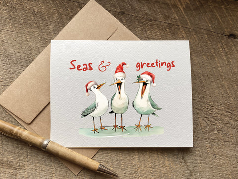 Christmas card with three birds wearing Santa hats and 'Seas & greetings' text 