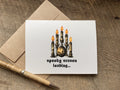 A halloween greeting card with a gothic style Halloween illustration of candles, a jack-o'-lantern, and the text 'spooky season loading.