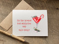 A funny christmas greeting card with a watercolor illustration of a red martini glass and the phrase 'Tis the season for Mistletoe and Alco-holly' 